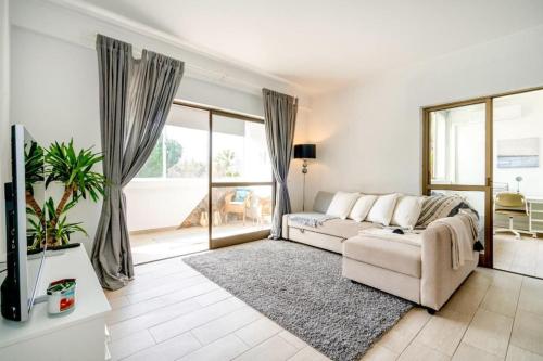 奎特里拉Spacious 1 bed in Vilamoura, Fast Wifi & Pool的带沙发和大窗户的客厅