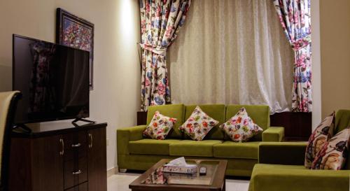 吉达Golden New Hira Hotel的客厅配有绿色沙发和电视