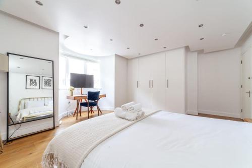 伦敦Stylish 3-bed near Camden Town & King's Cross的白色卧室配有一张大床和一张书桌