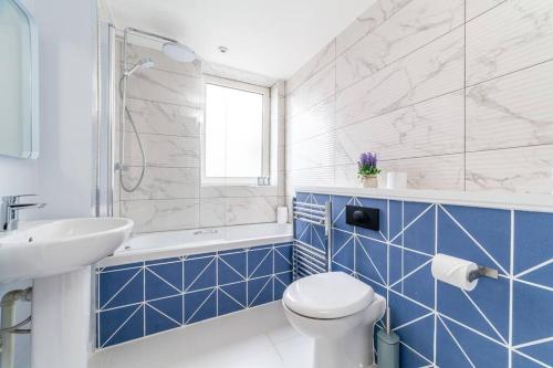 伦敦Stylish 3-bed near Camden Town & King's Cross的蓝色和白色的浴室设有卫生间和水槽