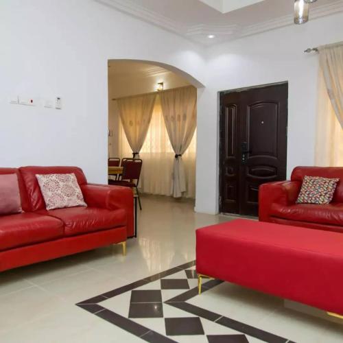 KwabenyanEdenRose home的客厅配有两张红色的沙发和一张桌子
