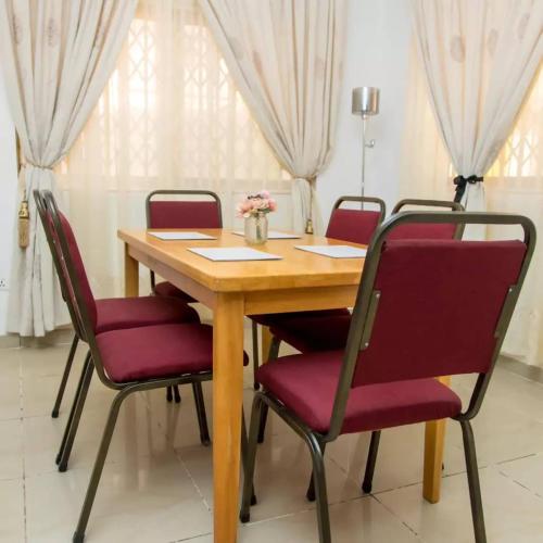 KwabenyanEdenRose home的一张木桌,配有红色椅子