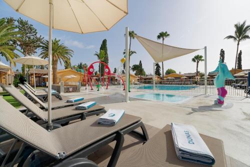 马斯帕洛马斯Suites & Villas by Dunas的一个带椅子和遮阳伞的游泳池的度假酒店