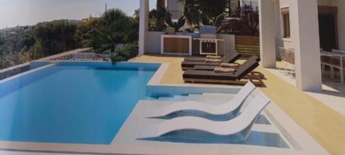 KorakiaíBay Overlook Akrotiri的一个带2把躺椅的游泳池以及1栋房子