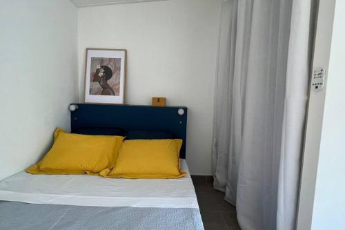 圣丹尼斯Le Pluméria - T1 avec un SPA privatif的一张带蓝色床头板和黄色枕头的床