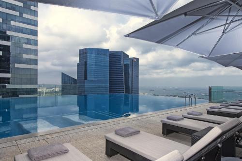 新加坡The Westin Singapore的一座带椅子和遮阳伞的游泳池