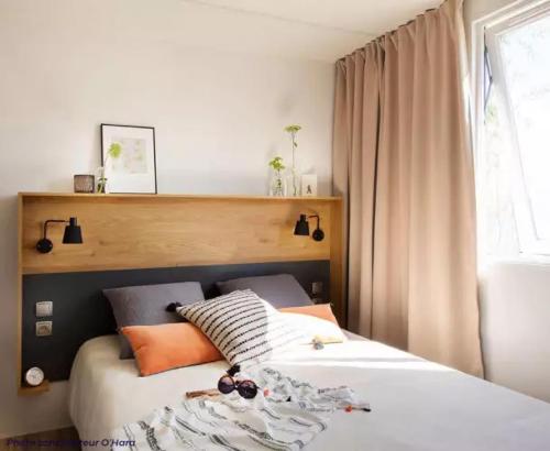 Salles-CuranMobilhome 4 étoiles - Piscine - eecfcg的一间卧室配有带橙色枕头的床和窗户。