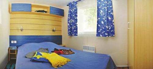 雷岛林滩Mobilhome 4 étoiles - Parc aquatique - eeia0f的一间卧室设有蓝色的床和窗户。