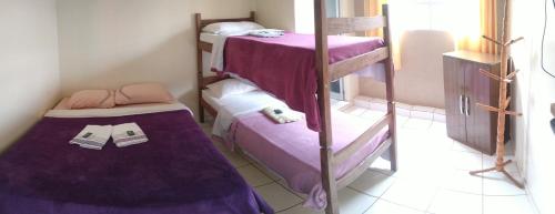 欧鲁普雷图Pousada Zacarias的配有紫色床单的客房内的两张双层床