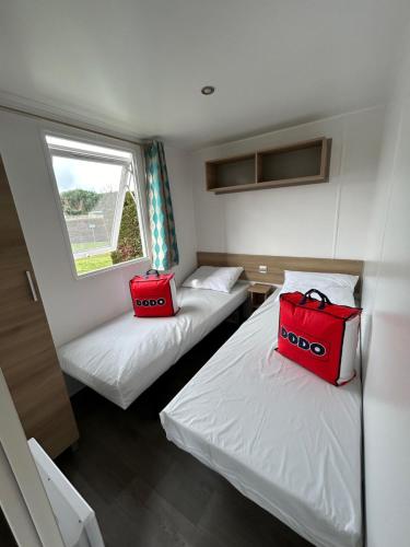 莱马特Mobil'home - Camping **** Les Charmettes的两个红色的袋子坐在房间里两张床上