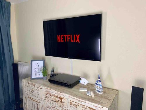 格拉尔-米里茨discovAIR Graal Müritz -Haus Quisisana- Strandnah mit Netflix的墙上的电视机,梳妆台上装有笔记本电脑