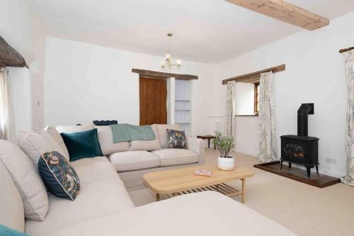 克雷迪顿Spacious country retreat in the heart of Devon.的客厅配有白色沙发和燃木炉。