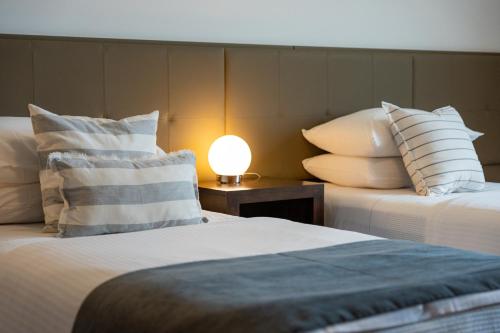 玛德琳港托洛萨酒店的一张桌子上灯的房间里两张床铺
