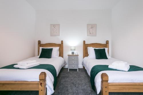 科廷厄姆Rio's Retreat的一间卧室配有两张带绿色和白色床单的床