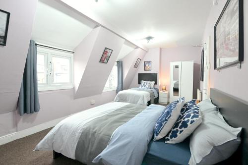 伦敦STUNNING 3 Bedroom Serviced Flat IN North London的一间卧室设有两张床和两个窗户。