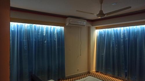 达卡Signature Home的一间设有蓝色窗帘和风扇的客房和一间客房