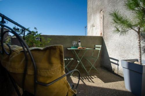 特雷布Lovely house with courtyard and terrace near canal du Midi的阳台配有带1瓶葡萄酒的桌子。