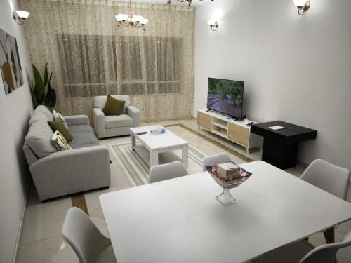 沙迦Smart Home Vacation Home的客厅配有白色桌子和电视