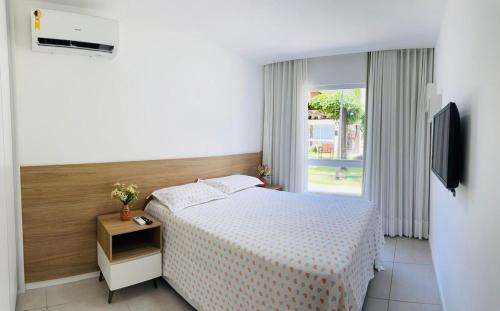 CamassariCondomínio Porto Smeralda的卧室配有白色的床和电视。