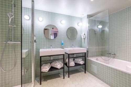 艾克斯莱班Urban Hotel & Spa Aix-les-Bains - BW Signature Collection的浴室配有2个盥洗盆、淋浴和浴缸。