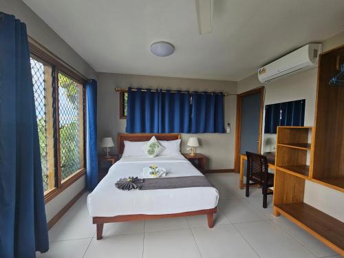 霍尼亚拉Sanalae Apartments的一间卧室配有一张带蓝色窗帘的大床