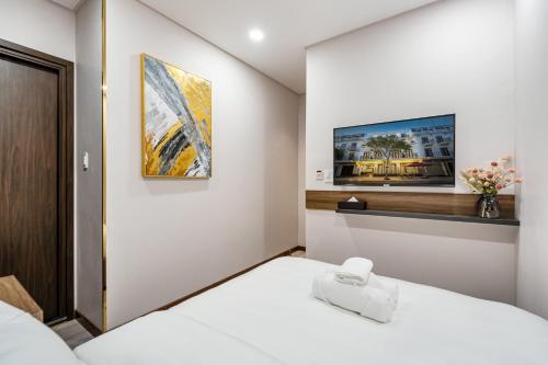 永隆VIN HOTEL的卧室配有白色的床和墙上的电视。