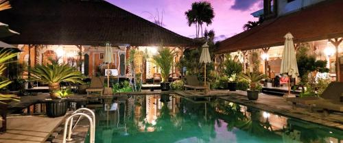 沙努尔斯塔那普瑞构琶酒店的度假村的游泳池,带椅子和树木