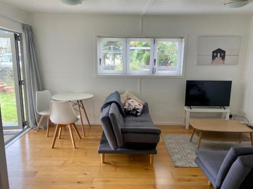 奥克兰Tranquil Nest Escape with deck and garden的客厅配有椅子、电视和桌子