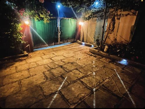 KharakvaslaBougain Villa- Sinhgad fort -Bedroom- Garden- Kitchen- AC- Wi-Fi-Parking-Khadakwasala Pune的石质庭院,晚上在栅栏上点灯