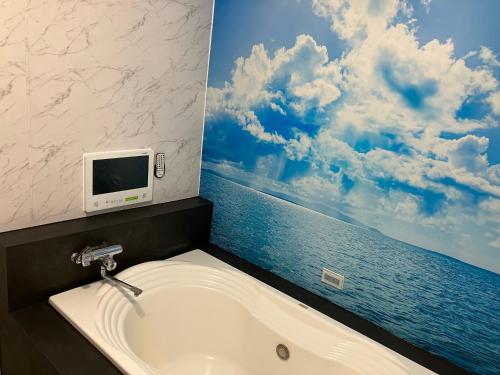 静冈Aegean Sea-Adults Only的带浴缸的浴室以及墙上的电视。