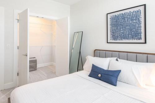 辛辛那提Cozysuites l Luxe 2BR in Downtown Cincinnati的一间白色卧室,床上配有蓝色枕头