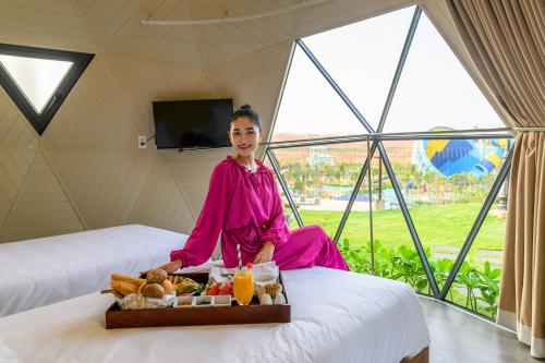潘切Wonderland Resort Phan Thiet的坐在床上的女人,带上一盘食物
