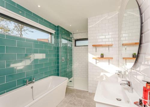 刘易斯Swanborough Lakes的带浴缸、水槽和镜子的浴室