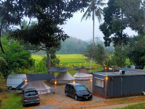 瓜拉江沙Tanah Merah Glamping Village (TMGV)的一群帐篷和汽车停在停车场