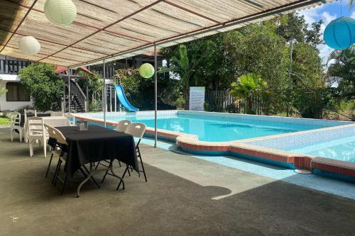 GuácimoHotel y restaurante Tabaconess的游泳池旁的游泳池配有桌椅
