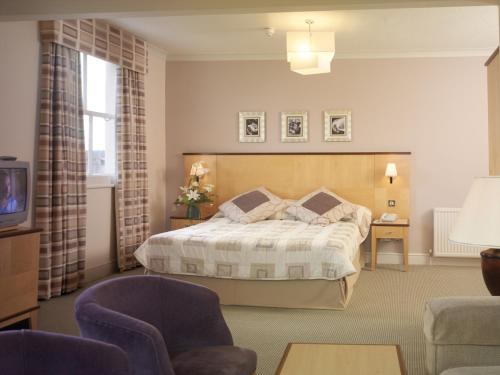 斯卡伯勒皇家酒店的一间卧室配有一张床、一张沙发和一台电视。