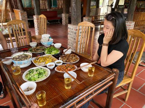 Homestay Bách Thảo Tà Lùng的坐在餐桌上吃盘子的女人