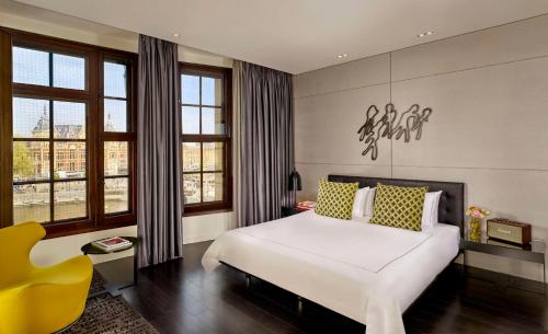 阿姆斯特丹art'otel amsterdam, Powered by Radisson Hotels的卧室配有白色的床和黄色椅子