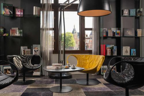 阿姆斯特丹art'otel amsterdam, Powered by Radisson Hotels的配有椅子、桌子和台灯的房间