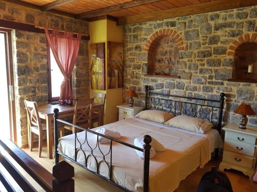 Avgonyma里克诺度假屋的一间卧室设有一张床和石墙