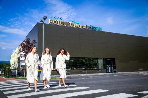卡鲁扎Hotel Thermal ŠÍRAVA的站在一幢楼前身的三名身着白色长袍的女性
