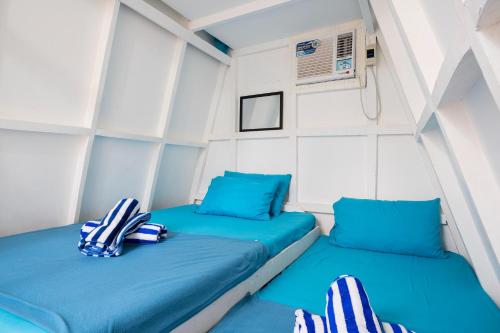 ZambalesCostas De Liwa Bar & Beach Resort的小客房内的两张床,配有蓝色枕头