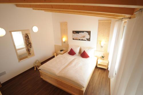 普拉托·阿罗·斯泰尔维奥Suvendes Apartments的一间卧室配有带白色床单和红色枕头的床。