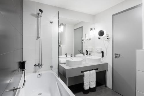 布达佩斯Akeah Verdi Budapest的浴室配有2个盥洗盆、淋浴和浴缸。