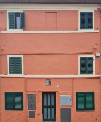 CastelferrettiLa Via del Castello的橙色的建筑,设有绿色百叶窗