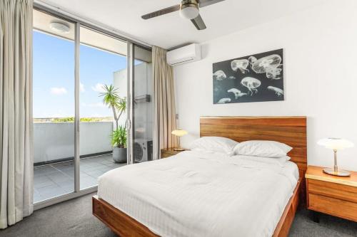 悉尼Spacious 2-Bed with Two Balconies with City Views的一间卧室设有一张床和一个大窗户