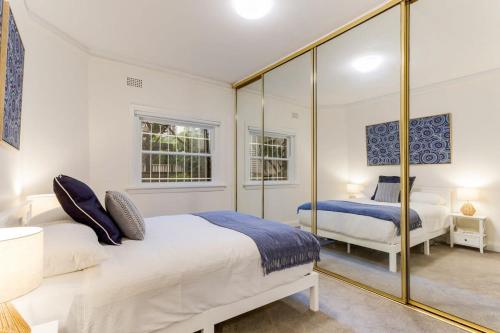 悉尼Art Deco Apartment Meters Away From The Beach的一间卧室设有两张床和大镜子