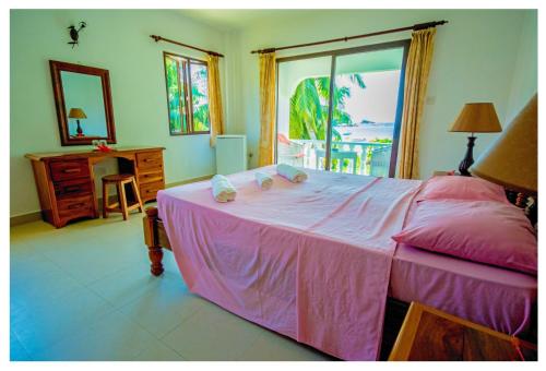 普拉兰罗斯玛丽宾馆的卧室配有粉红色的床、书桌和窗户。