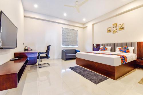斋浦尔FabHotel Pravaasam Residency的一间卧室配有一张床、一张书桌和一台电视。