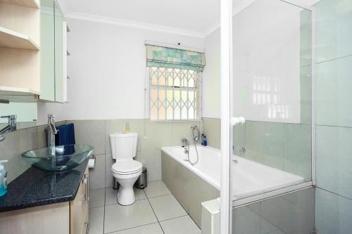 约翰内斯堡Corner House large 1 bedroom apartment的浴室配有卫生间、浴缸和水槽。